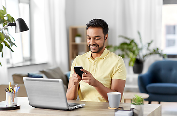 Image showing happy indian man with smartphone at home office