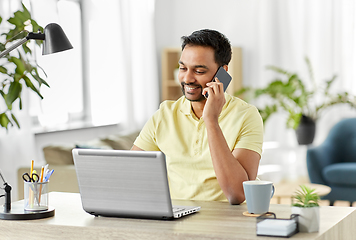 Image showing happy man calling on smartphone at home office