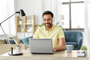 Image showing man in headphones with laptop working at home