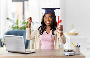 Image showing graduate student with laptop and diploma at home