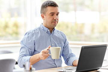 Image showing man with laptop drinking coffee at home office