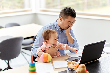 Image showing father with baby working on laptop at home office