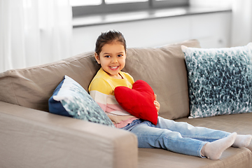Image showing happy little girl with heart shaped pillow at home