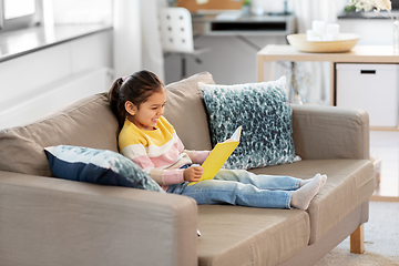 Image showing happy smiling little girl reading book at home