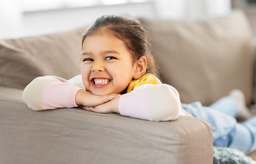 Image showing happy smiling little girl lying on sofa at home