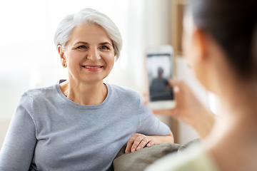 Image showing adult daughter photographing senior mother at home