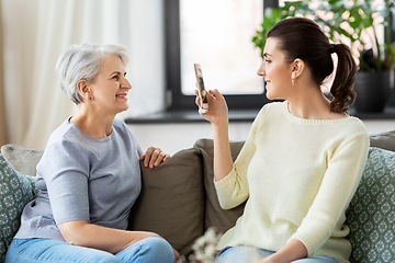 Image showing adult daughter photographing senior mother at home