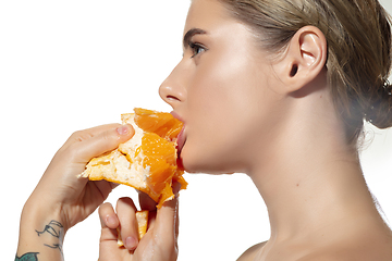 Image showing Energy. Close up of beautiful young woman biting juicy orange over white background. Cosmetics and makeup, natural and eco treatment, skin care.
