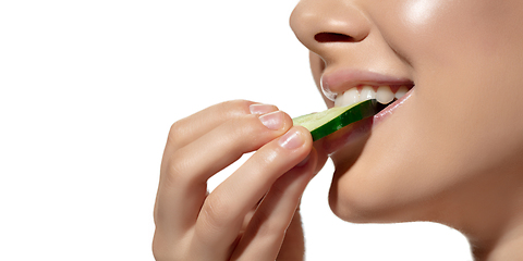 Image showing Freshness. Close up of beautiful young woman biting cucumber\'s slice over white background. Cosmetics and makeup, natural and eco treatment, skin care. Flyer, proposal.