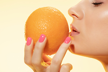 Image showing Close up of beautiful female face with orange over yellow background. Cosmetics and makeup, natural and eco treatment, skin care.