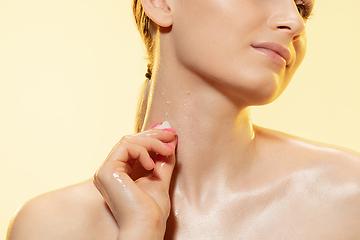 Image showing Close up of beautiful woman with melting ice cube over yellow background. Cosmetics and makeup, natural and eco treatment, skin care.