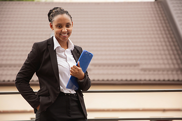 Image showing African-american businesswoman in office attire smiling, looks confident and happy, successful