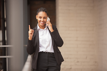 Image showing African-american businesswoman in office attire smiling, looks confident and happy, successful