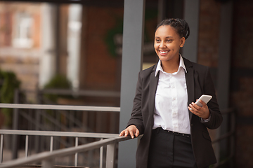 Image showing African-american businesswoman in office attire smiling, looks confident and happy, successful