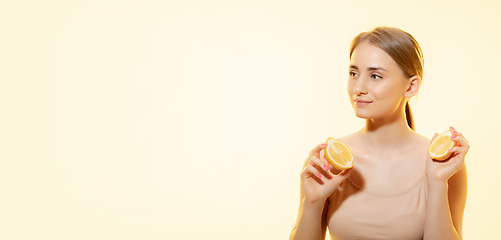 Image showing Freshness. Close up of beautiful female face with lemon slices over yellow background. Cosmetics and makeup, natural and eco treatment, skin care. Flyer with copyspace.