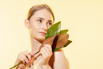 Image showing Feminine. Close up of beautiful female face with green leaves over white background. Cosmetics and makeup, natural and eco treatment, skin care.