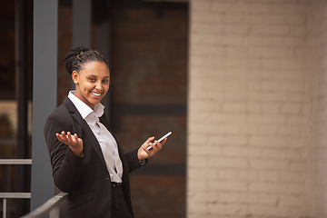 Image showing African-american businesswoman in office attire smiling, looks confident and happy, successful