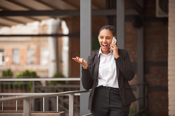 Image showing African-american businesswoman in office attire smiling, looks confident and happy, successful