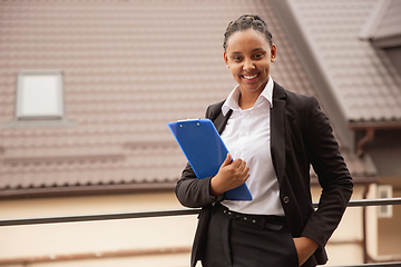 Image showing African-american businesswoman in office attire smiling, looks confident and happy, successful