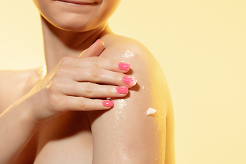 Image showing Tender skin. Close up of beautiful woman with moisturizer over yellow background. Cosmetics and makeup, natural and eco treatment, skin care.