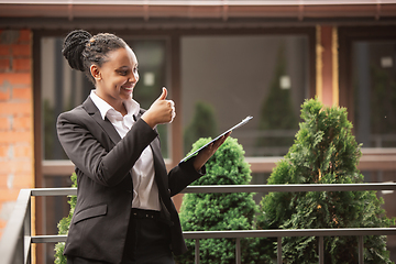 Image showing African-american businesswoman in office attire smiling, looks confident and happy, successful