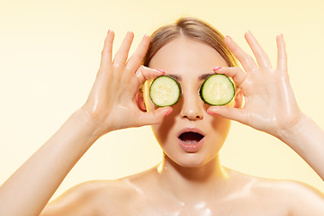 Image showing Green. Close up of beautiful female face with cucumber slices over yellow background. Cosmetics and makeup, natural and eco treatment, skin care.