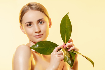 Image showing Feminine. Close up of beautiful female face with green leaves over white background. Cosmetics and makeup, natural and eco treatment, skin care.