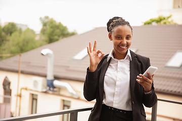 Image showing African-american businesswoman in office attire smiling, looks confident and happy, successful