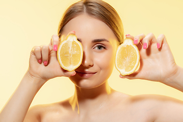 Image showing Choosing eco. Close up of beautiful female face with lemon slices over yellow background. Cosmetics and makeup, natural and eco treatment, skin care.