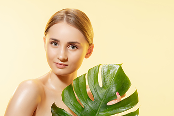 Image showing Spa. Close up of beautiful female face with green leaves over white background. Cosmetics and makeup, natural and eco treatment, skin care.