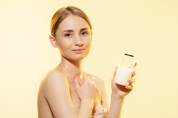 Image showing Shining. Close up of beautiful woman with moisturizer over yellow background. Cosmetics and makeup, natural and eco treatment, skin care.