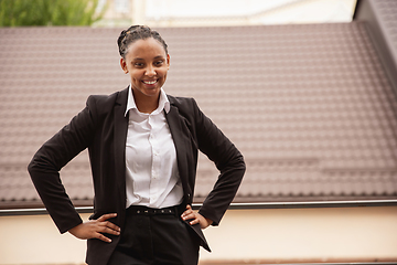 Image showing African-american businesswoman in office attire smiling, looks confident and happy, successful