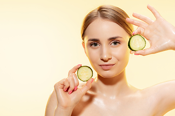 Image showing Green. Close up of beautiful female face with cucumber slices over yellow background. Cosmetics and makeup, natural and eco treatment, skin care.