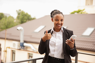 Image showing African-american businesswoman in office attire smiling, looks confident and happy, successful