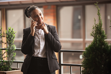 Image showing African-american businesswoman in office attire smiling, looks confident and happy, successful