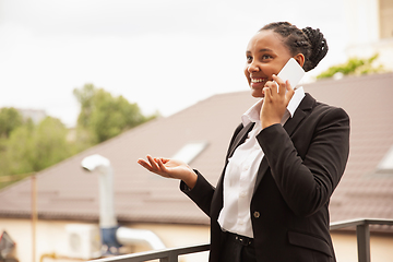 Image showing African-american businesswoman in office attire smiling, looks confident and happy, successful