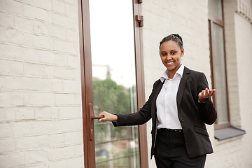 Image showing African-american businesswoman in office attire smiling, looks confident and happy, successful