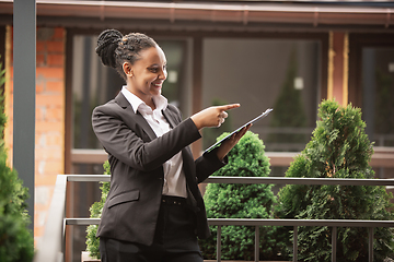 Image showing African-american businesswoman in office attire smiling, looks confident and happy, successful