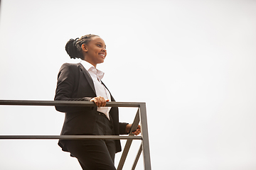 Image showing African-american businesswoman in office attire smiling, looks confident and happy, successful