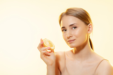 Image showing Citrus. Close up of beautiful female face with lemon slices over yellow background. Cosmetics and makeup, natural and eco treatment, skin care.