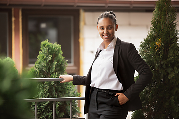 Image showing African-american businesswoman in office attire smiling, looks confident and happy, successful