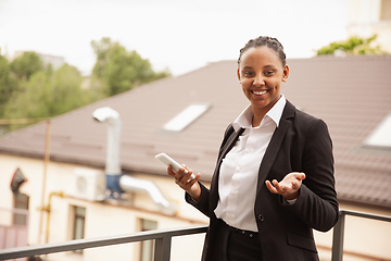 Image showing African-american businesswoman in office attire smiling, looks confident and happy, successful