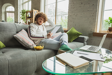 Image showing Manager or student working from home while being insulated or keep quarantine \'cause of coronavirus COVID-19. Reading report, task, sitting on sofa.