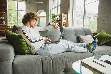 Image showing Manager or student working from home while being insulated or keep quarantine \'cause of coronavirus COVID-19. Typing text, lying down on sofa.