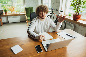 Image showing Manager or student working from home while being insulated or keep quarantine \'cause of coronavirus COVID-19. Making notes.