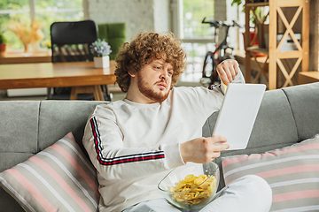 Image showing Manager or student working from home while being insulated or keep quarantine \'cause of coronavirus COVID-19. Reading report, task, sitting on sofa.