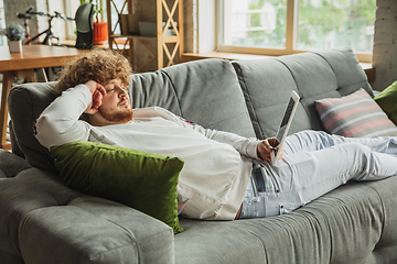 Image showing Manager or student working from home while being insulated or keep quarantine \'cause of coronavirus COVID-19. Reading report, task, sitting on sofa.