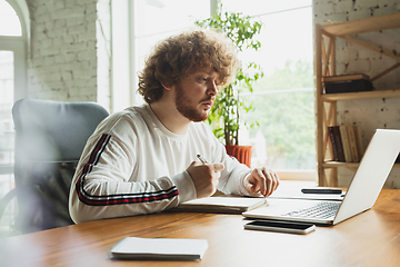 Image showing Manager or student working from home while being insulated or keep quarantine \'cause of coronavirus COVID-19. Making notes.