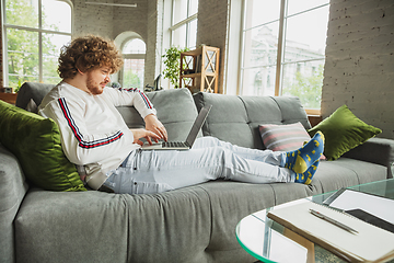 Image showing Manager or student working from home while being insulated or keep quarantine \'cause of coronavirus COVID-19. Typing text, lying down on sofa.