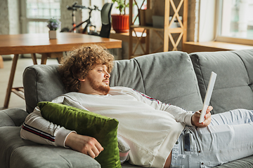 Image showing Manager or student working from home while being insulated or keep quarantine \'cause of coronavirus COVID-19. Reading report, task, sitting on sofa.